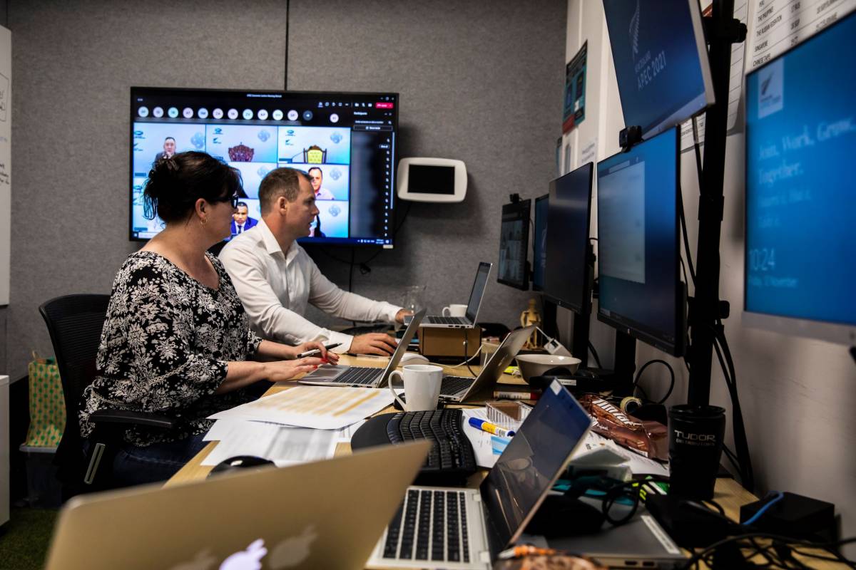 People looking at computer and television screens in a media control room. 