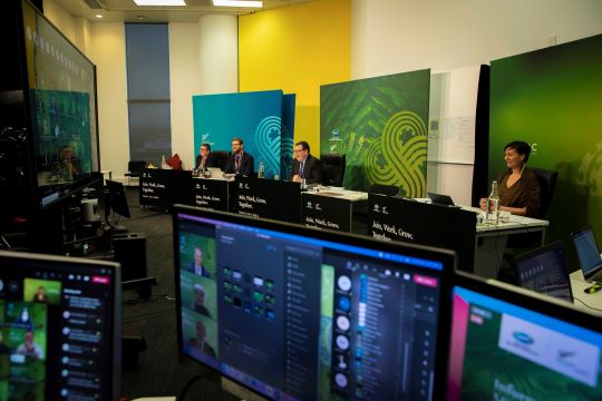 Behind the scenes of the APEC 2021 Informal Finance Ministerial Meeting with ABAC showing computer screens and people sitting at desks. 