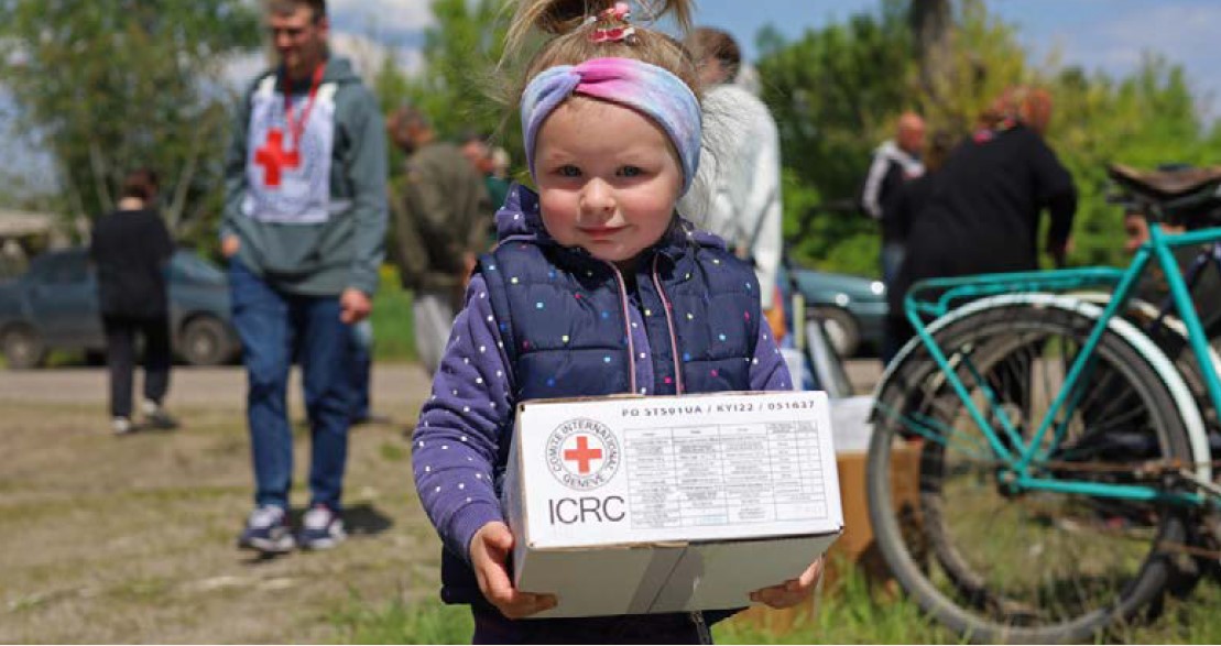 A Ukrainian child holding a Red Cross food parcel. 