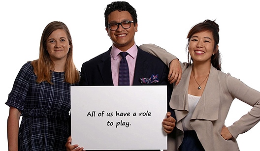 An image of three professionals, holding a sign which reads: "All of us have a role to play.". 