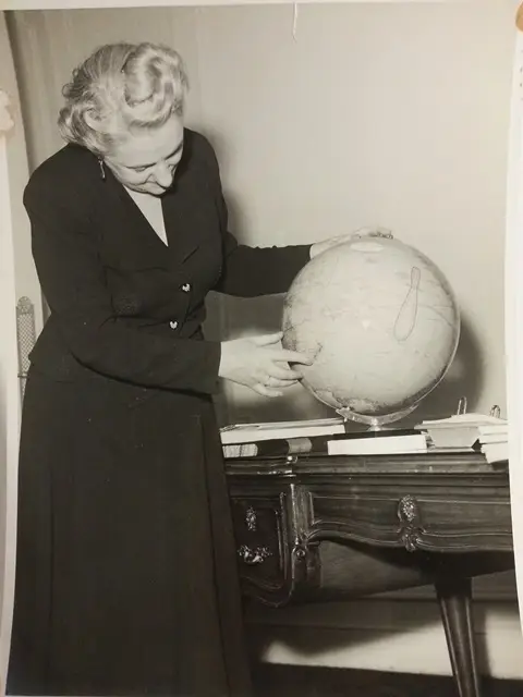 An image of Jean McKenzie pointing out a location on a globe..