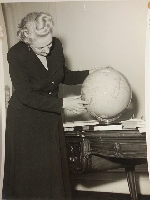 An image of Jean McKenzie pointing out a location on a globe..