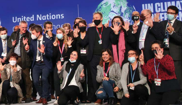 An image of NZ negotiators celebrating with others after agreement on the Glasgow Climate Pact was reached. .