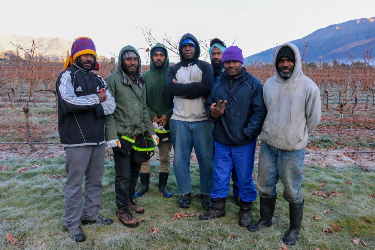 An image of seven men in a field, posing for the photo. 