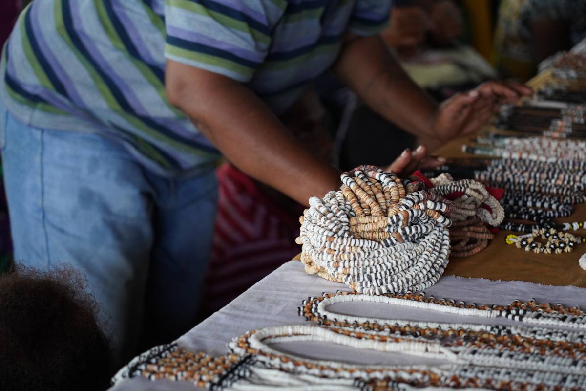 An image of a person standing at a display table full of beaded necklaces and jewelry. . 