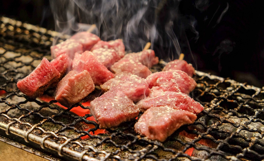 An image of beef fillets cooking on a grill.