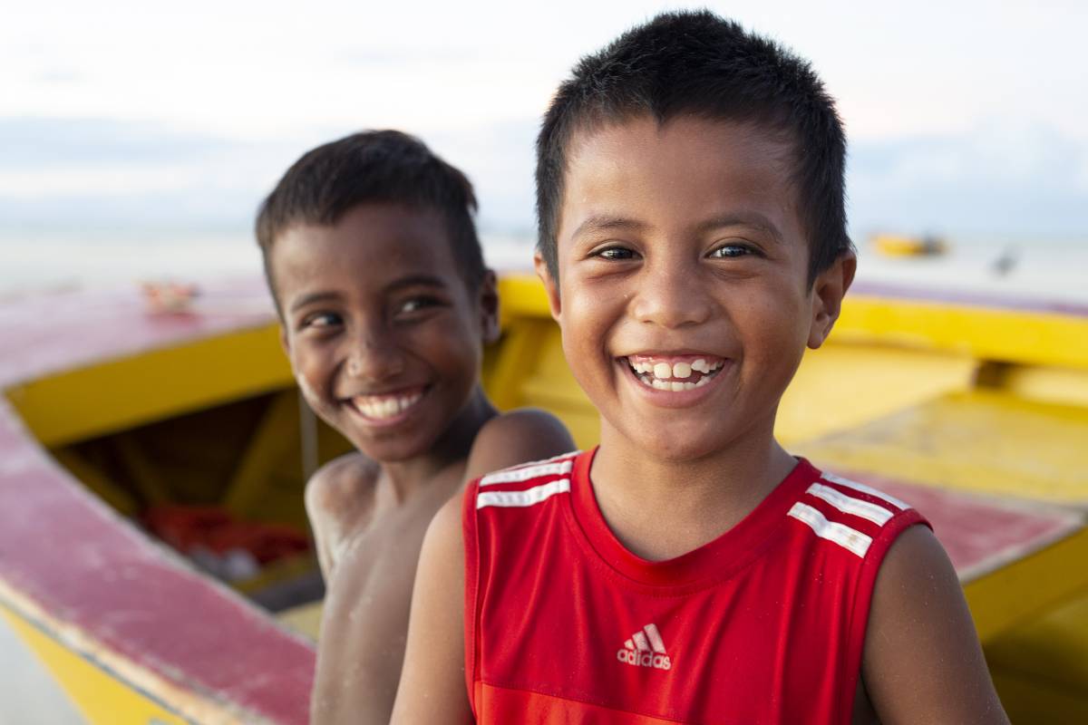 Two young boys smiling on a beach in Kiribati. 