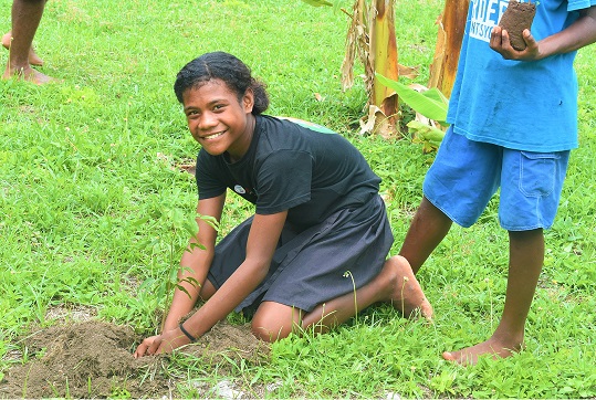 A young girl planting a tree. 